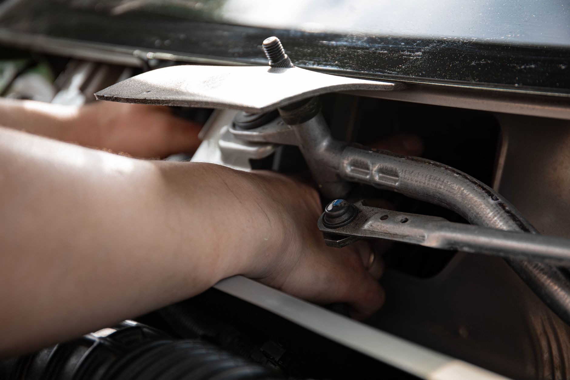 Mechanic completing tow bar fitting UK under car chassis